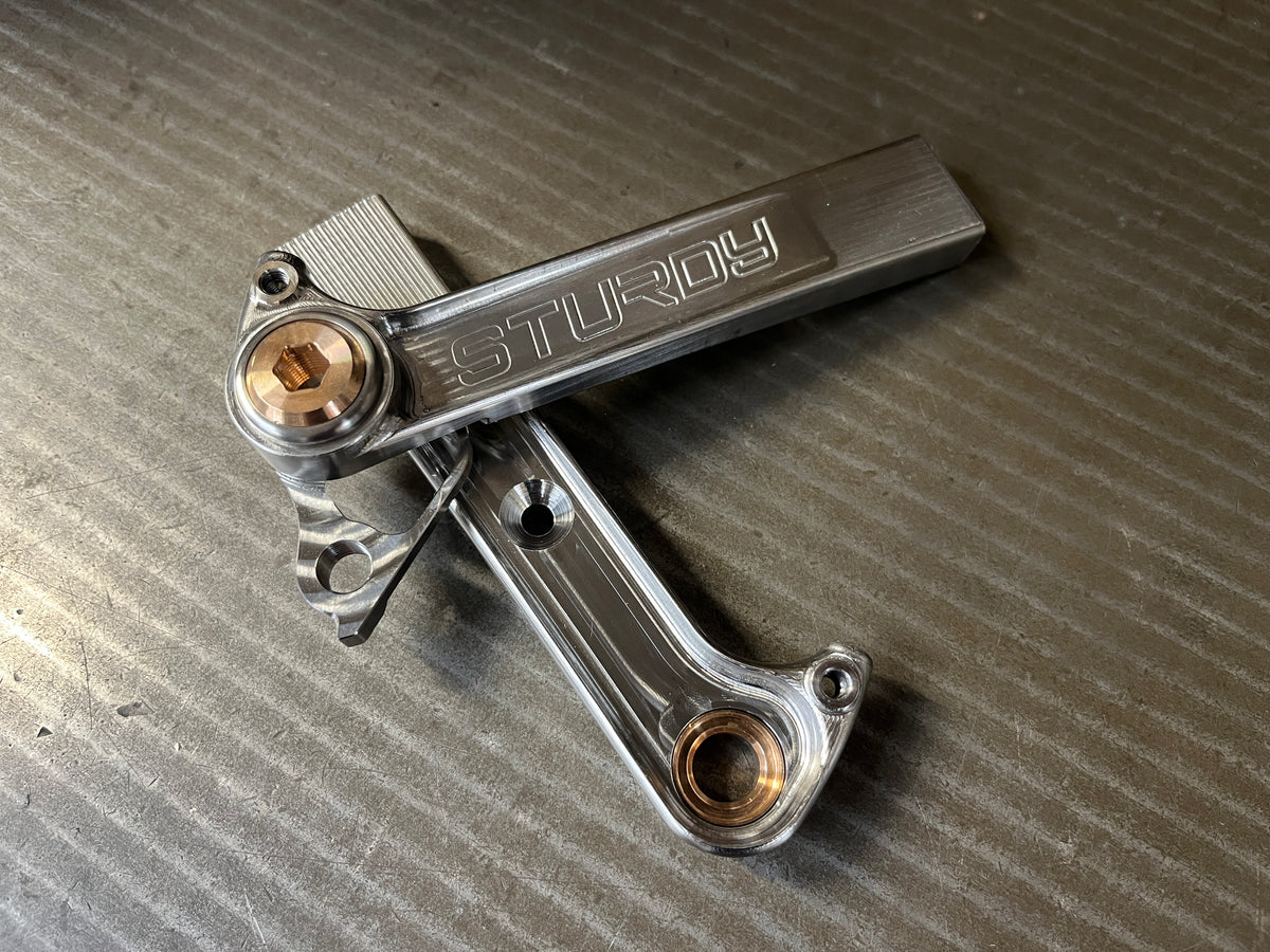 Pair of machined titanium rear dropouts with Sturdy engraving and phosphor bronze axle inserts