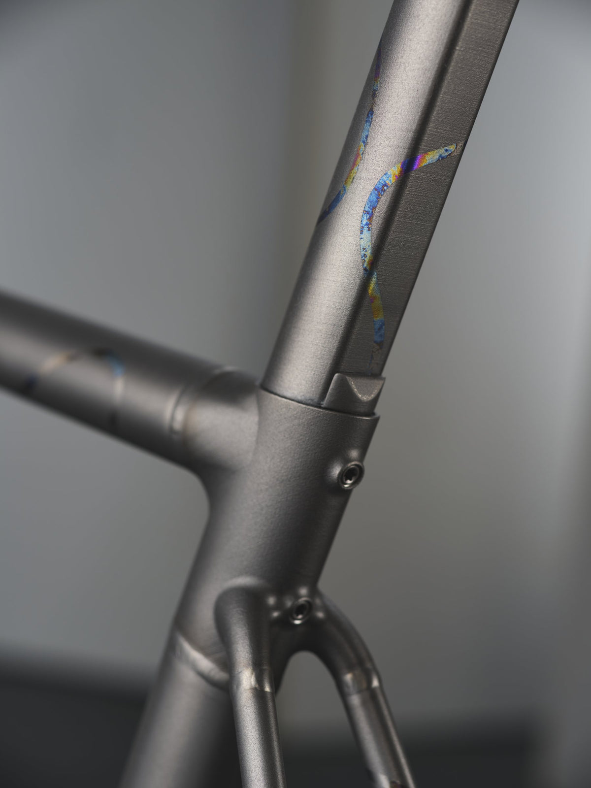 Shot-peened titanium seat cluster with rainbow anodised swirling graphics on the seat tube