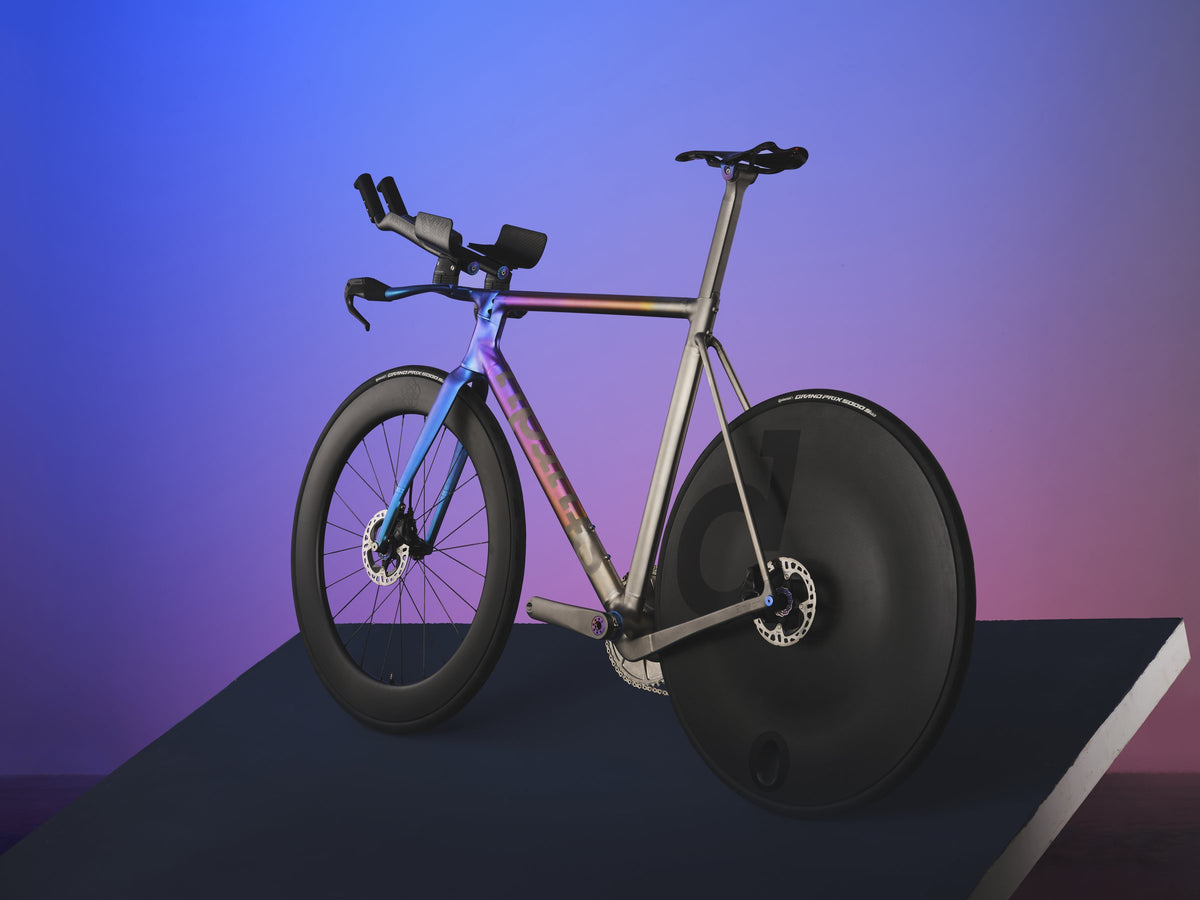 Titanium time trial bike with blue-purple anodised front end and disc rear wheel on a raised platform