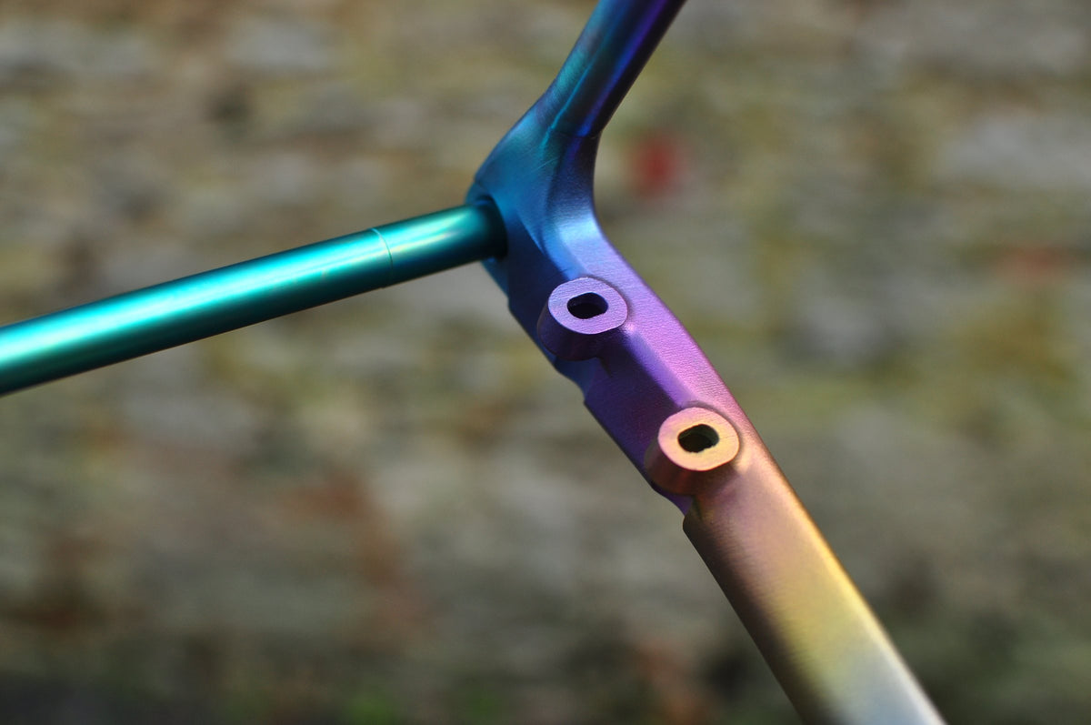 Frame junction with mounting bosses in a teal, purple and gold anodised titanium fade
