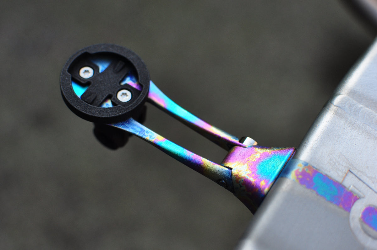 Rainbow anodised titanium computer mount with black cradle, out-front from a brushed titanium stem