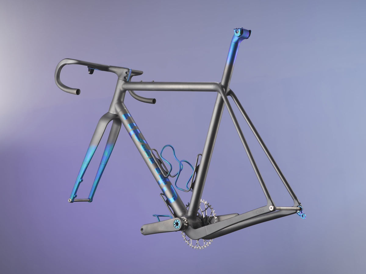 Dark grey titanium road frameset with blue anodised logo, fork tips, seatpost and cages on a purple backdrop