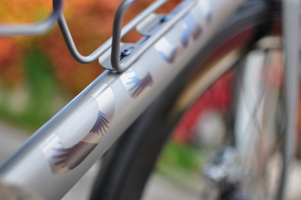 Titanium down tube with purple and blue anodised wing motifs under a bottle cage