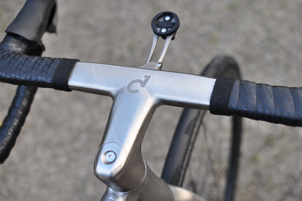 Brushed titanium integrated handlebar with etched logo and out-front computer mount, seen from above