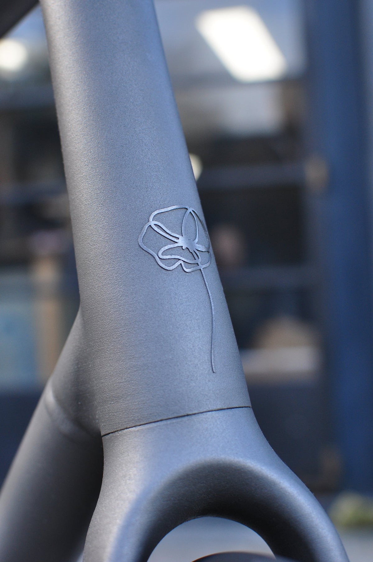 Shot-peened titanium seat tube with a fine-line etched poppy flower above the seat stays
