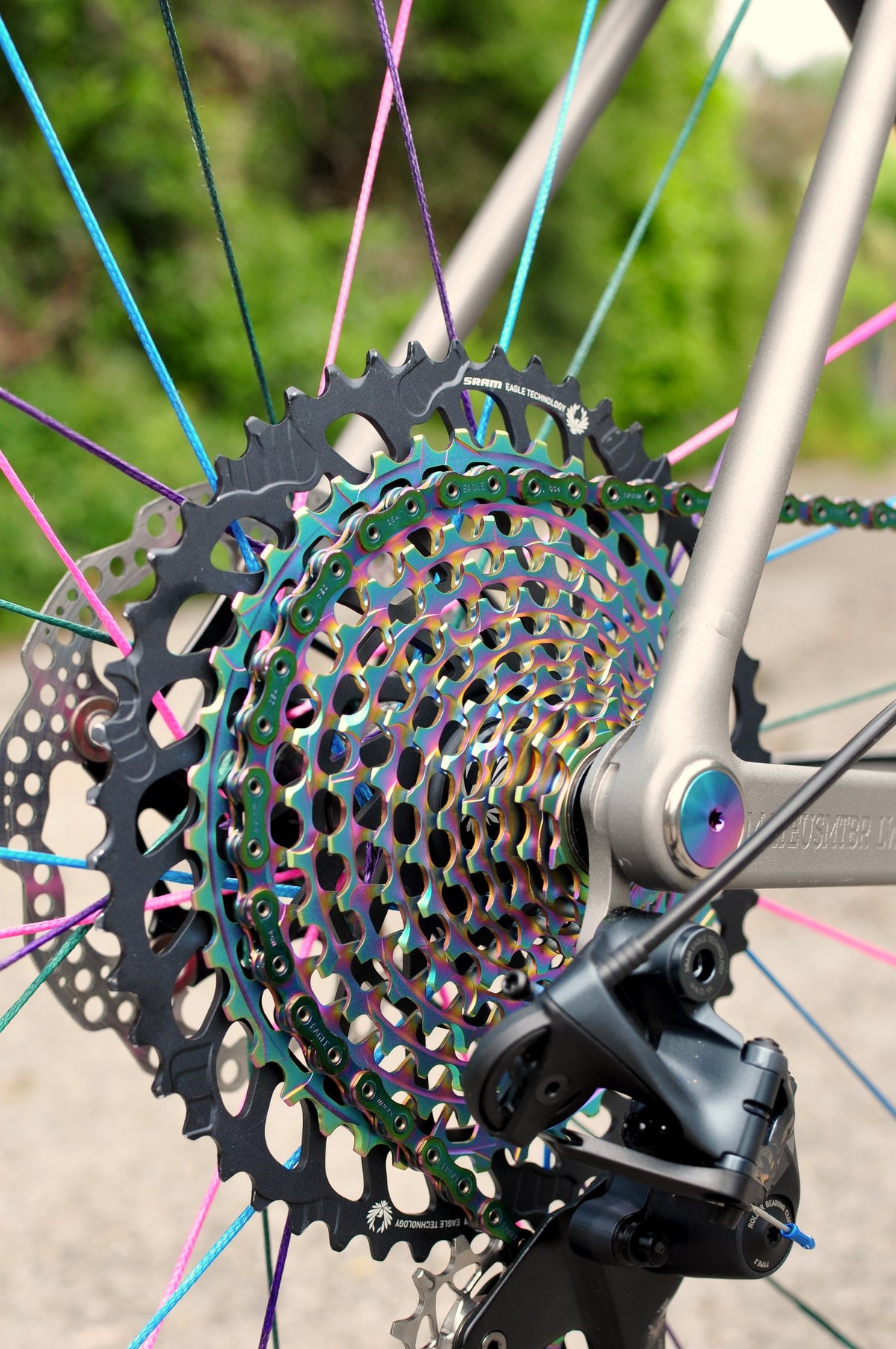 Rainbow oil-slick cassette and chain on a titanium frame with multicoloured spokes