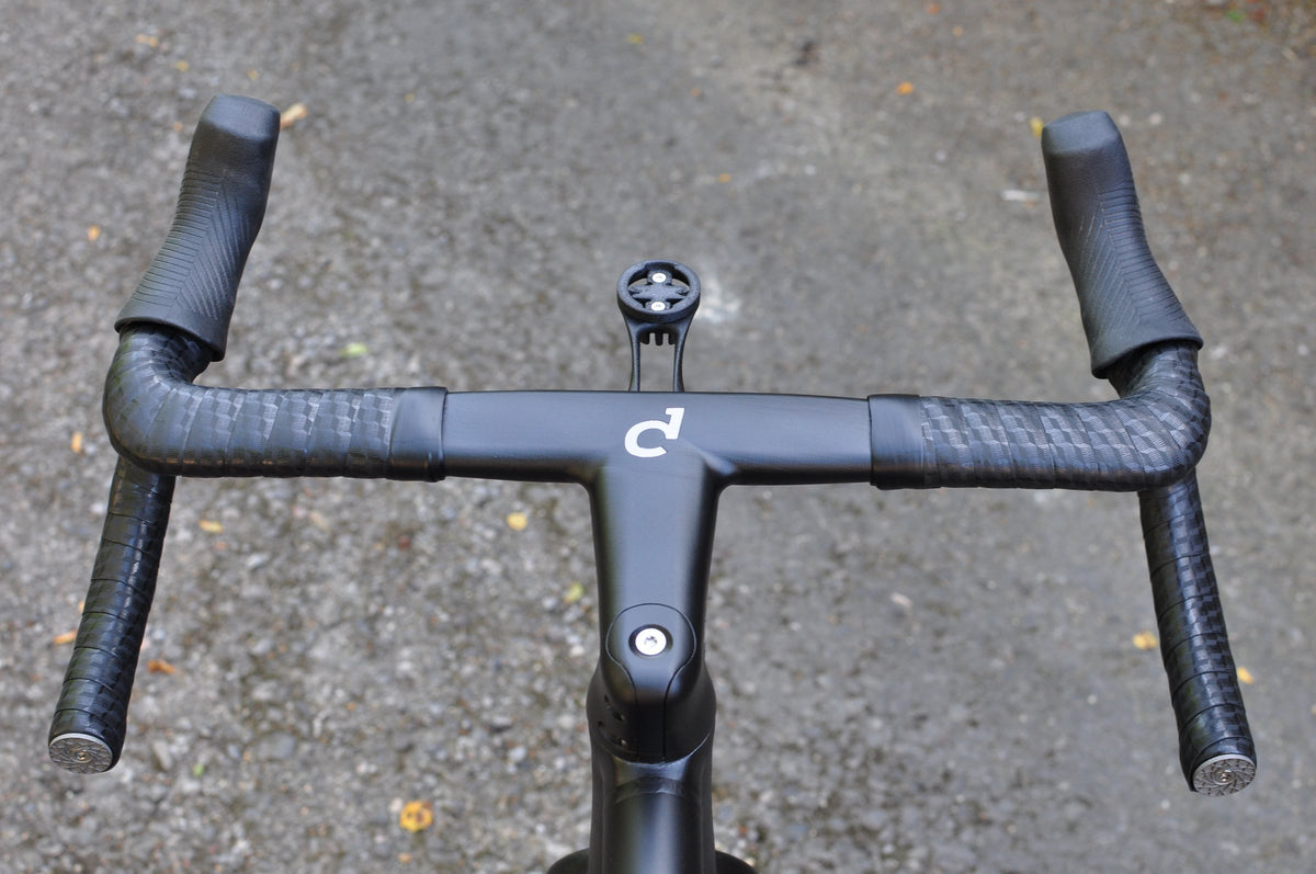 Black integrated drop handlebar and stem with white logo and computer mount, seen from above