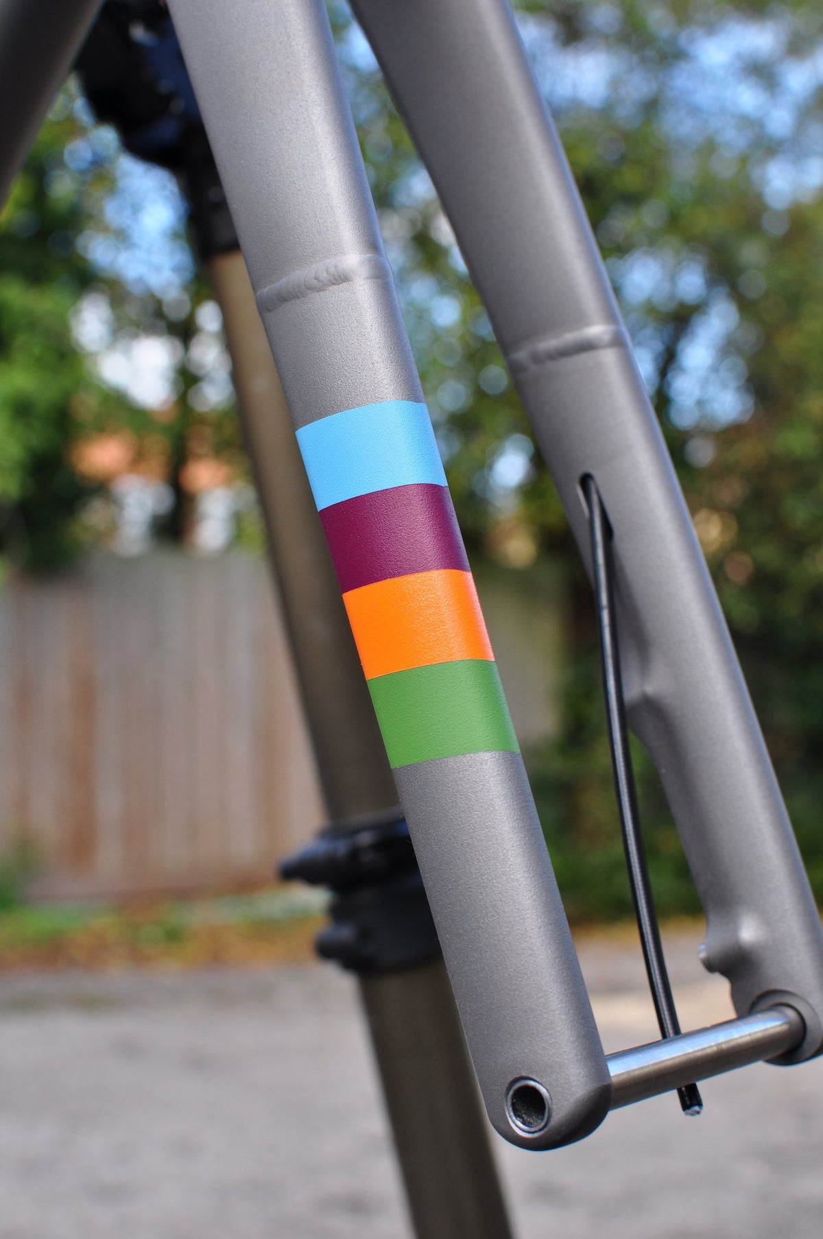 Shot-peened titanium fork leg with blue, plum, orange and green painted stripes