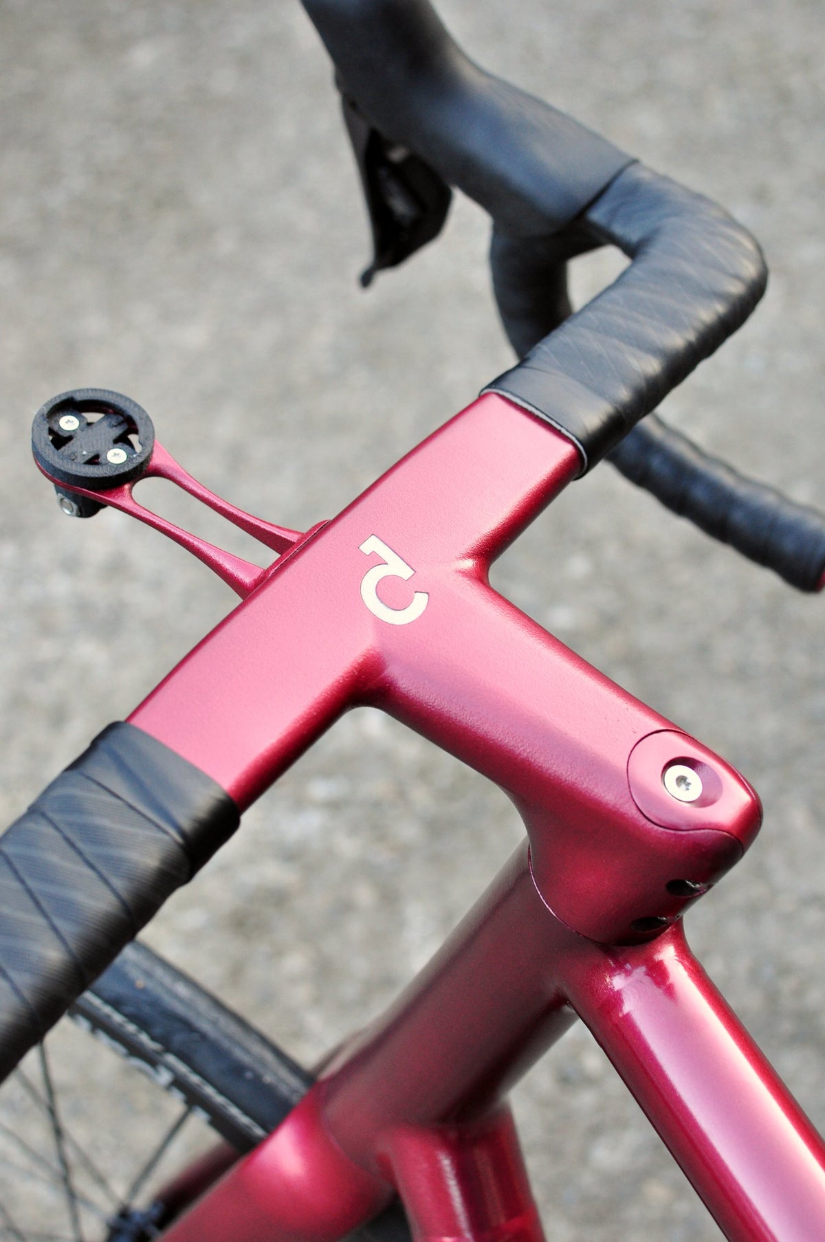 Metallic red one-piece bar and stem with Sturdy logo, black bar tape and computer mount