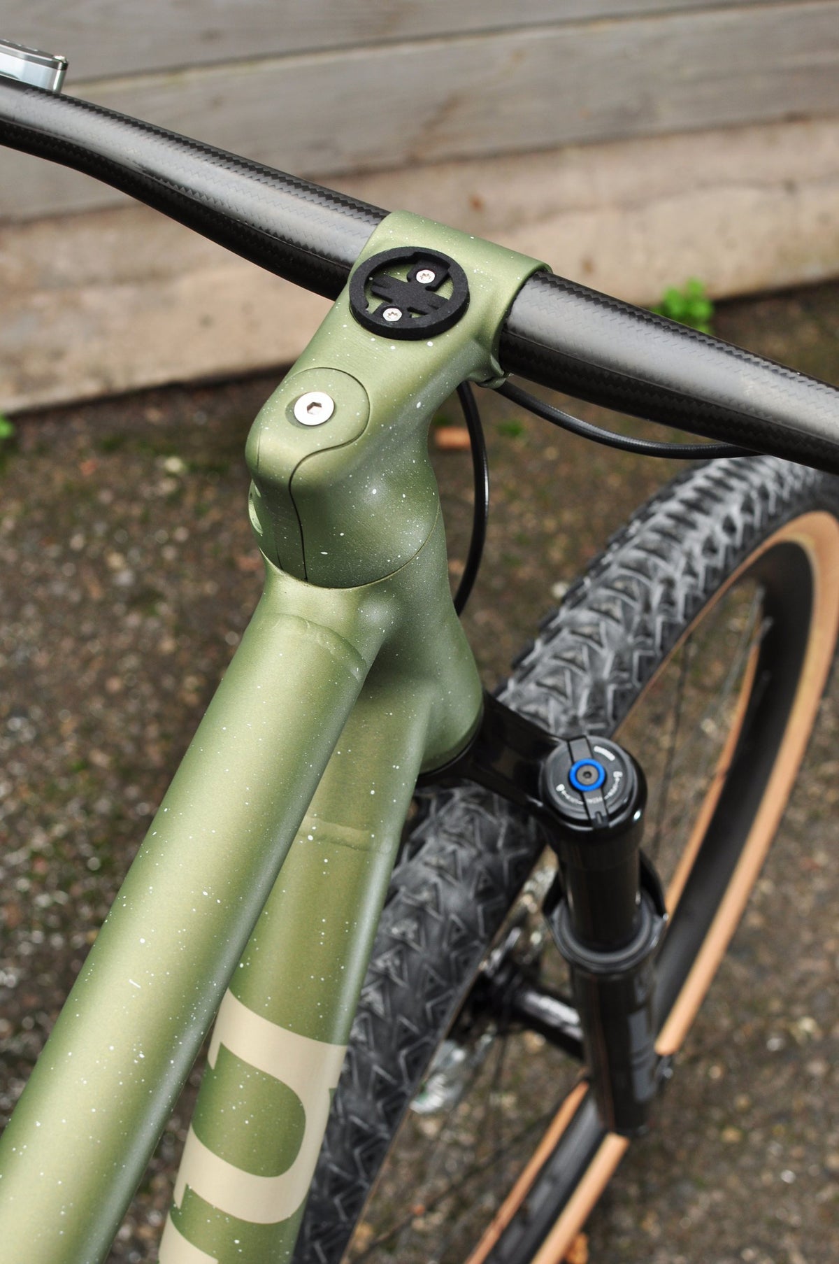 Olive green speckled one-piece stem and head tube on a mountain bike with black suspension fork