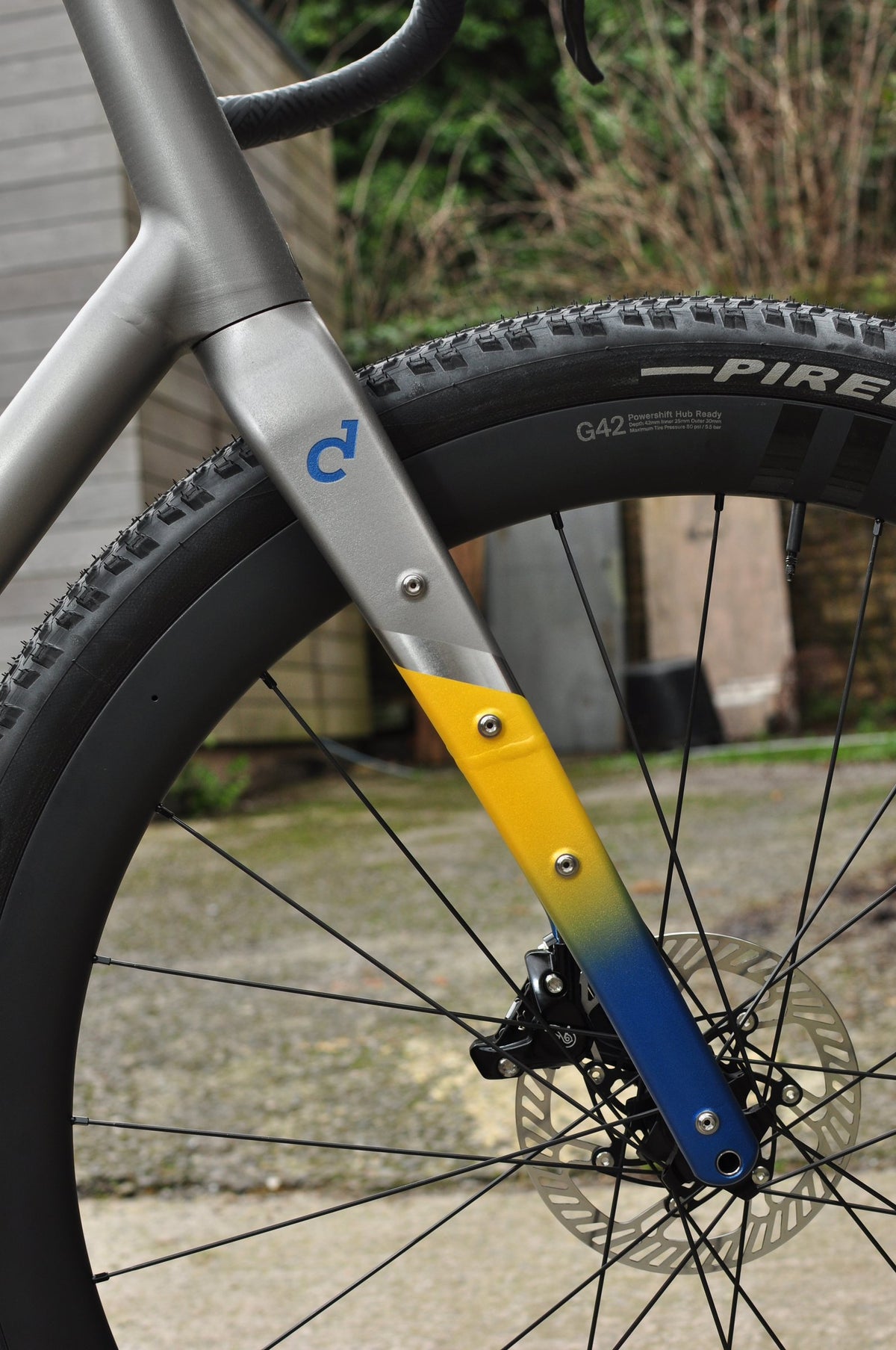 Titanium gravel fork with blue Sturdy logo and a yellow-to-blue painted fade on the lower leg